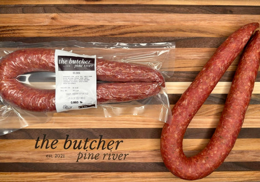 Two packages of sausages on a wooden cutting board with 'the butcher pine river' branding.